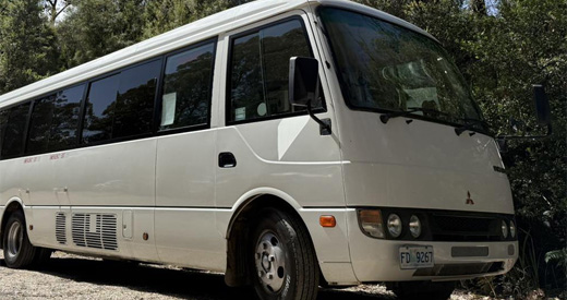 buses_0004__0000_Mitsubishi Rosa (2005) Mitsubishi Rosa minibus parked on gravel in front of gum trees